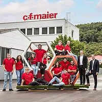 Eine Gruppe Azubis posiert gemeinsam mit der Geschäftsführung vor dem Hauptsitz der C.F. Maier-Firmengruppe